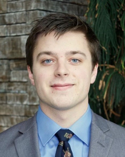 A photo of Andrew. He is a young white man and is directly facing the camera, partly smiling.